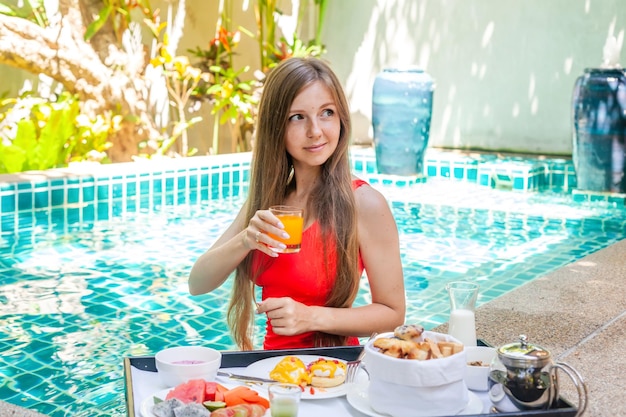 Young beautiful woman have breakfast in private pool on villa at luxury resort