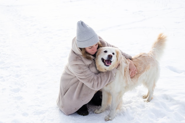 Young beautiful woman and her golden retriever dog having fun in winter