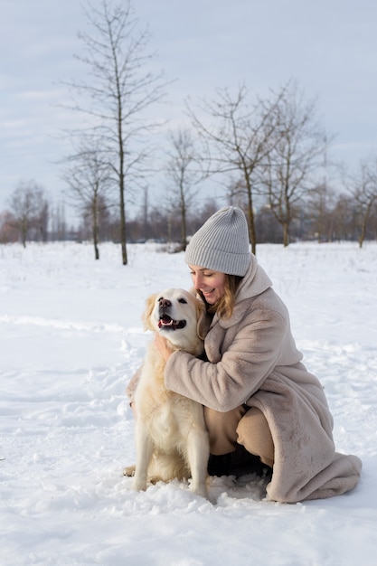 Young beautiful woman and her golden retriever dog having fun in winter