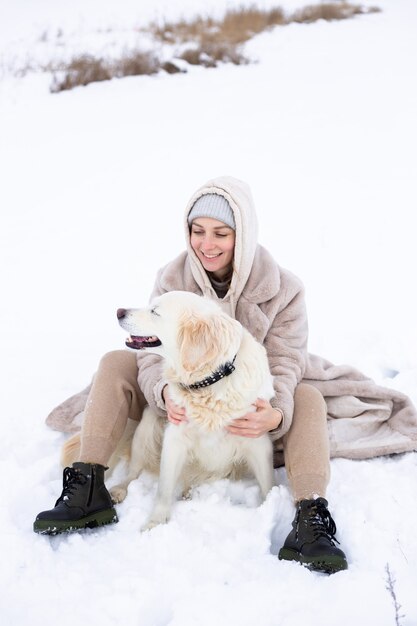 Young beautiful woman and her golden retriever dog having fun in winter