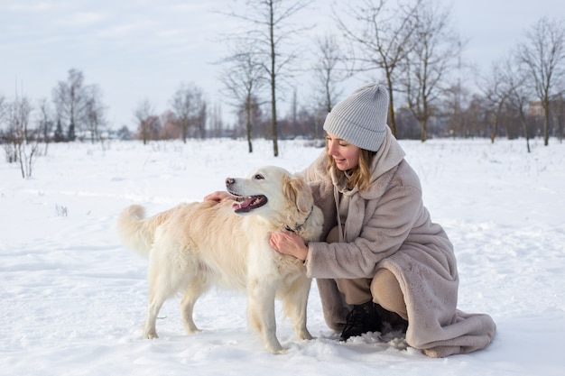 Young beautiful woman and her golden retriever dog having fun in winter