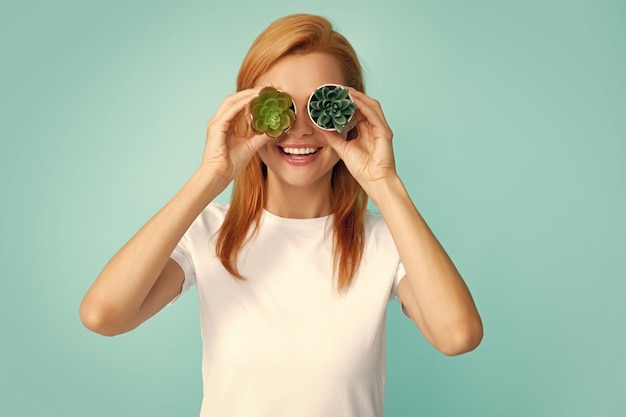 Young beautiful woman holding cactus pot over isolated blue background