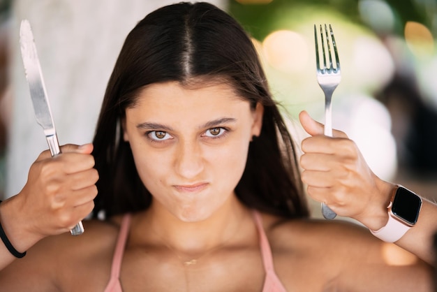 Young beautiful woman holding a knife and a fork