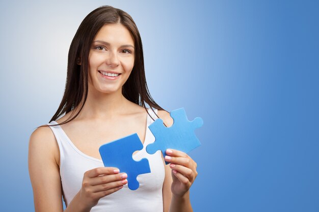 Young beautiful woman  holding piece of puzzle