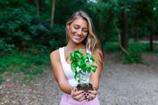 Young beautiful woman holding a plant growing out of soil