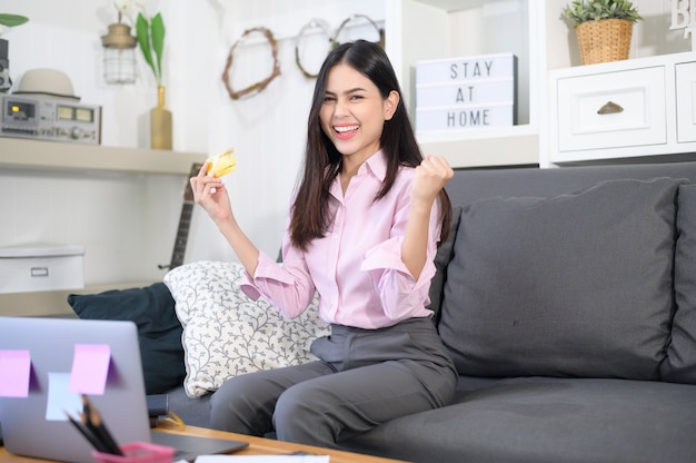 A young beautiful woman is using credit card for online shopping on internet website at home, e-commerce concept