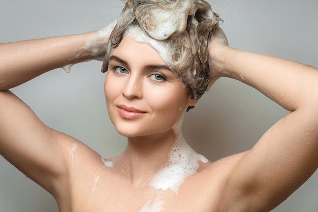 Young beautiful woman is washing her hair with a shampoo