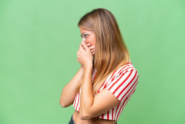 Young beautiful woman over isolated background covering mouth and looking to the side