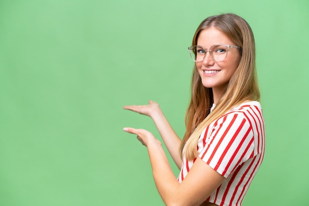 Young beautiful woman over isolated background extending hands to the side for inviting to come