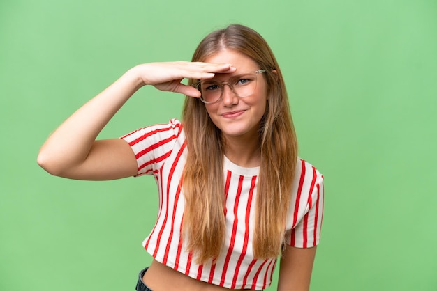 Young beautiful woman over isolated background looking far away with hand to look something