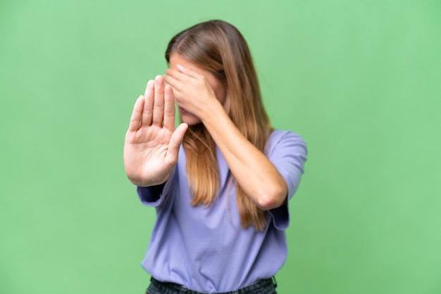 Young beautiful woman over isolated background making stop gesture and covering face