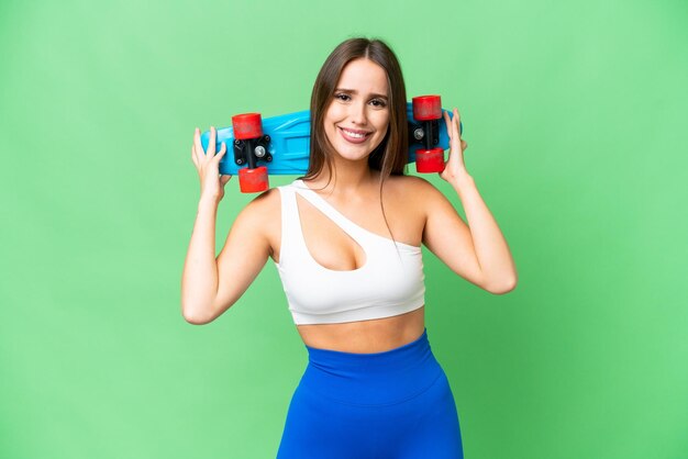 Young beautiful woman over isolated chroma key background with a skate with happy expression