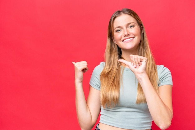 Young beautiful woman isolated on red background pointing to the side to present a product