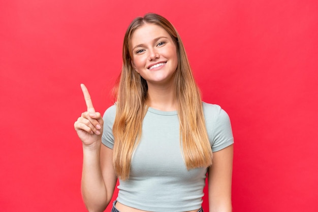 Young beautiful woman isolated on red background showing and lifting a finger in sign of the best