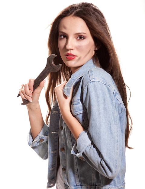 Young beautiful woman in jeans jacket with wrench