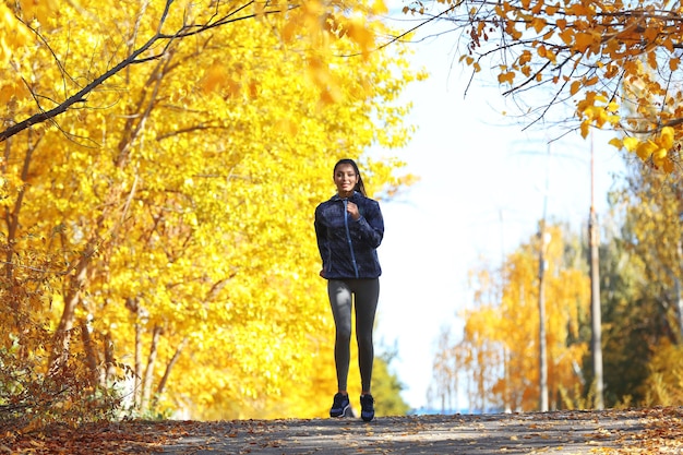 Young beautiful woman jogging in autumn park