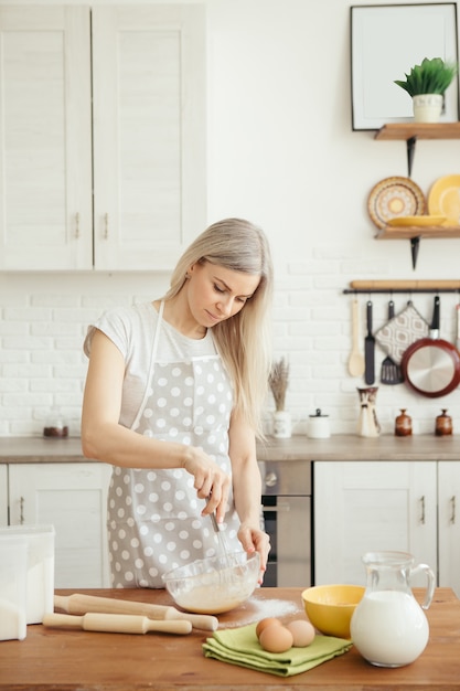 Young beautiful woman kneads dough for baking cookies in the kitchen. Toning.