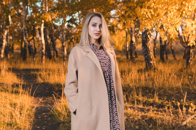 Young beautiful woman in long coat in autumn forest