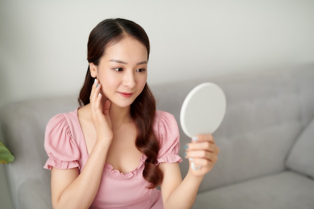 Young beautiful woman looking in the mirror at the living room