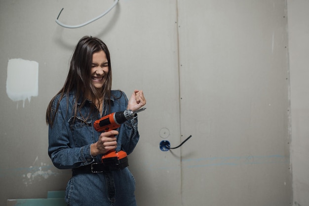 Young beautiful woman makes repairs in the apartment the girl makes repairs at home on her own paint...