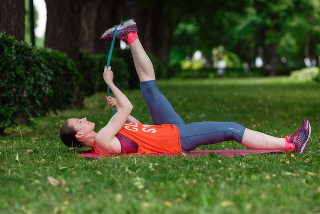 Young beautiful woman meditates on a summer day in the park Idea and concept of calm in a busy city and a healthy lifestyle stretching and preparing for a run in the park