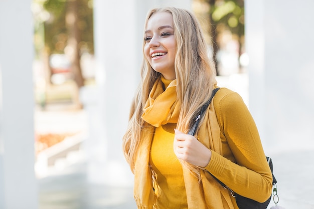 Young beautiful woman  outdoors. Closeup portrait of cheerful ladyon spring or autumn background. Girl with backpack.