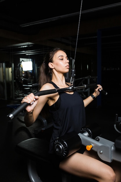 Young beautiful woman performs exercise in modern gym club