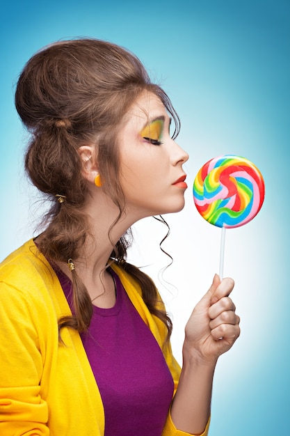 Young beautiful woman reaching for a colorful lollipop