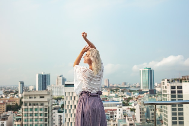 Young beautiful woman on the roof of a multi storey hotel with a view of the city