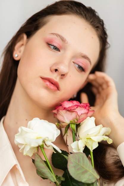 Young beautiful woman smelling a bunch of red roses. fashion interior photo of beautiful smiling woman with dark hair holding a big bouquet of red roses in Valentine's day