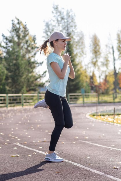 A young beautiful woman in sportswear plays sports at a local stadium