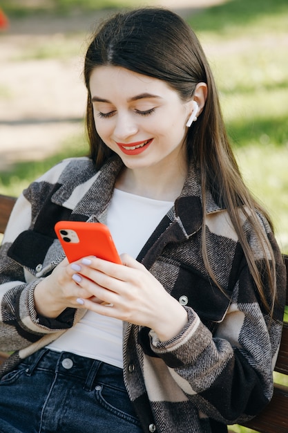 Young beautiful woman standing on a bench using the phone