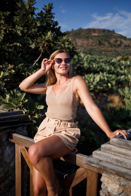 A young beautiful woman stands on the observation deck with a stunning view of the green grove