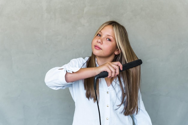 Young beautiful woman straightening her long hair