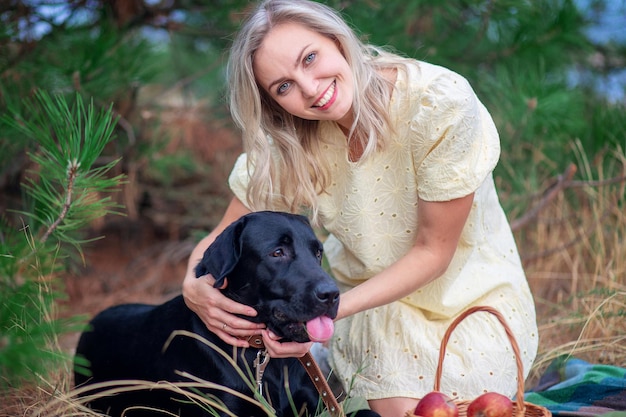 Young beautiful woman in a summer dress walks with her labrador dog. Happy woman hugging with her big dog on the street