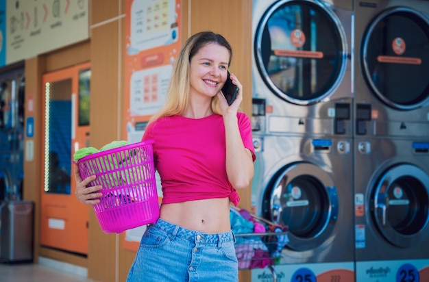 Young beautiful woman talking by the phone in the laundry