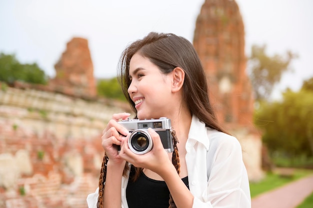 Young beautiful woman traveling and taking photo at thai historical Park