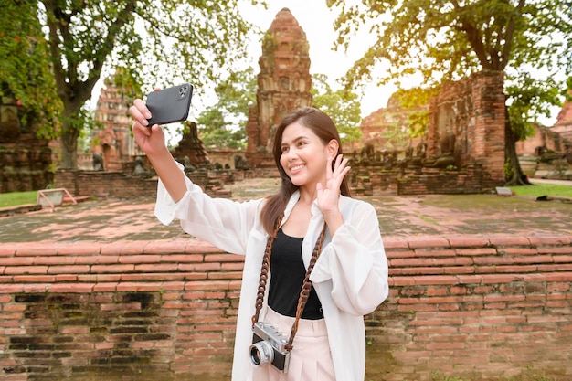 Young beautiful woman traveling and taking photo at thai historical Park