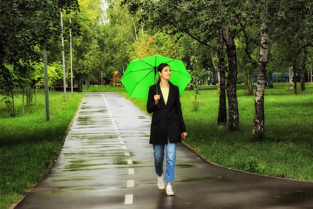 Young beautiful woman walking under a green umbrella