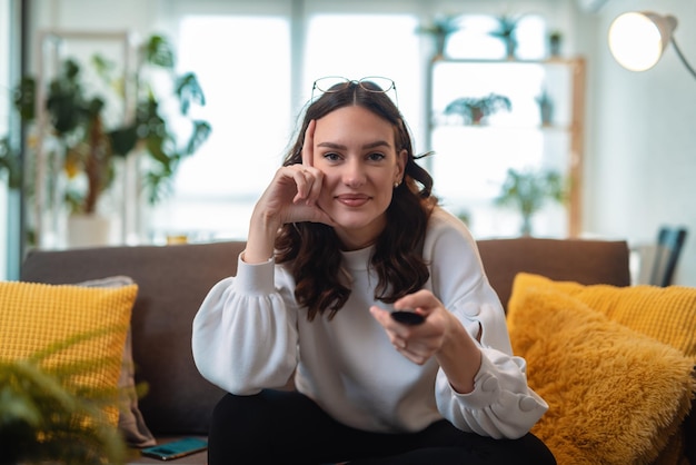 Young beautiful woman watching TV at home