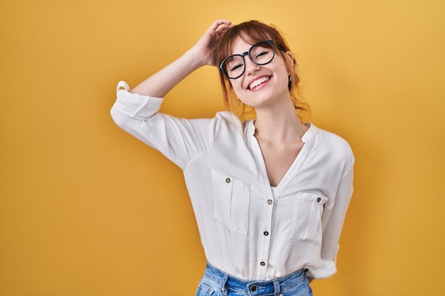 Young beautiful woman wearing casual shirt over yellow background smiling confident touching hair with hand up gesture, posing attractive and fashionable