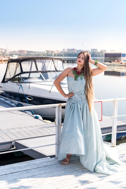 Photo young beautiful woman wearing dress and posing with yacht