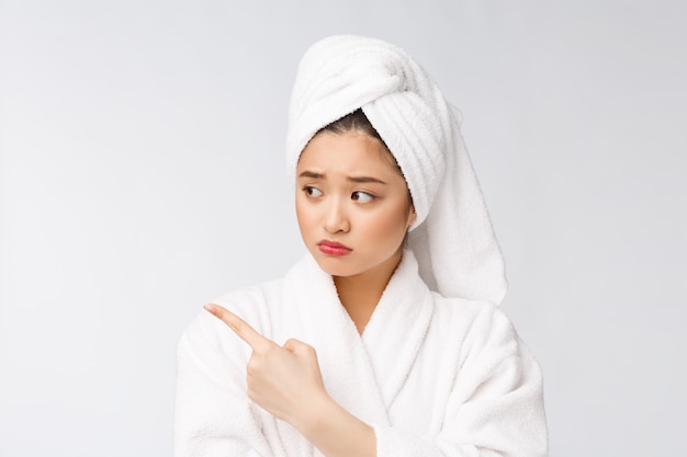 Young beautiful woman wearing shower towel after bath over isolated white wall pointing with finger.