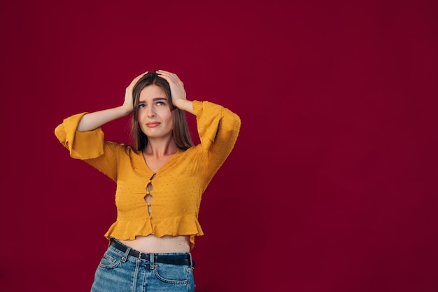 Young beautiful woman wearing yellow blouse hold to the head depressed and worried about distress crying Sad expression