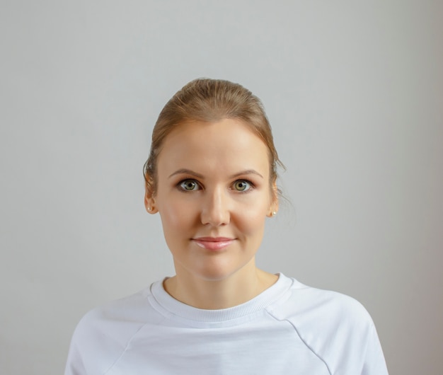 Young beautiful woman in white clothes on a light background.