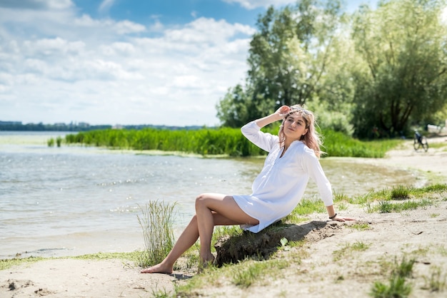 Young beautiful woman in white dress enjoy nature near the lake, freedom. summer day