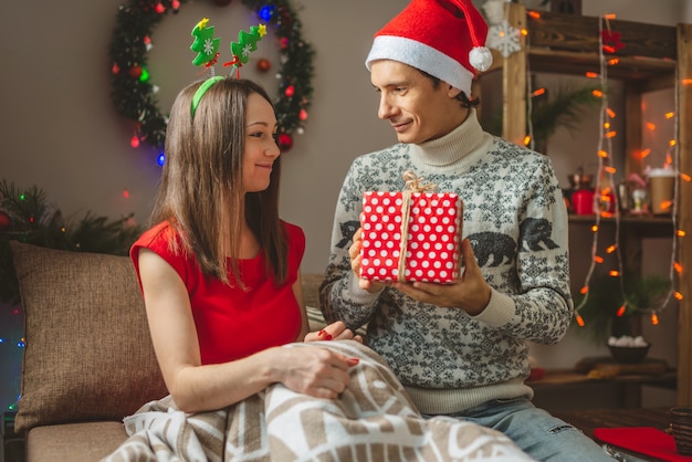 Young beautiful woman wife gives her husband a surprise gift box