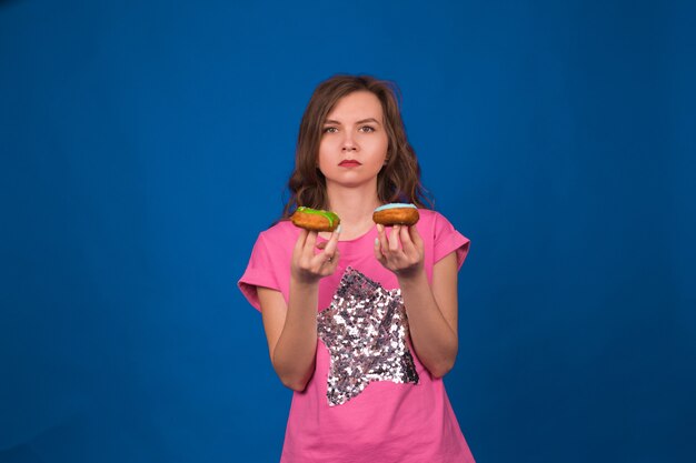 Young beautiful woman with doughnut on blue