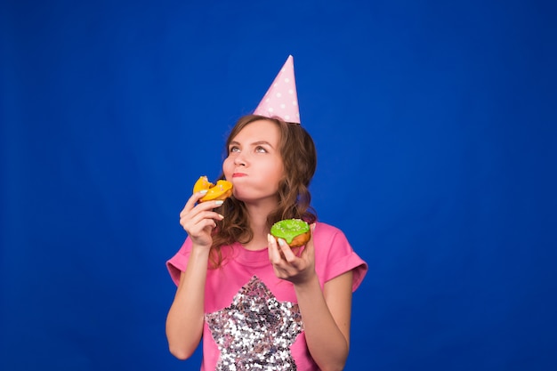 Young beautiful woman with doughnut on blue