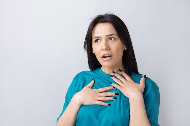 Young beautiful woman with facial expression of surprise standing over gray background.